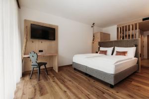 キウーザにあるWeingut & Genusshotel Spitalerhof Superiorのベッドルーム(ベッド1台、デスク、テレビ付)