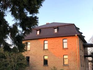 a red brick building with a black roof at Domaine Séquoia in Stutzheim