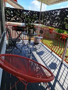 Un balcón con una silla roja y una mesa en una terraza. en Armies apartment, en Sarina