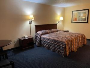 um quarto de hotel com uma cama, uma mesa e candeeiros em Budget Inn Temple Hills em Temple Hills