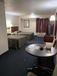 a hotel room with two beds and a table at Budget Inn Temple Hills in Temple Hills