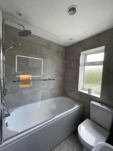 哈羅蓋特的住宿－Modern Cottage Style House with Log Burner，浴室配有白色浴缸和卫生间。