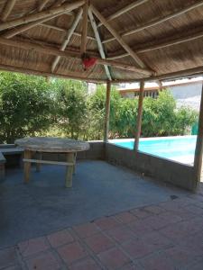 a picnic table under a pergola next to a pool at Flor Silvestre in Valle Hermoso