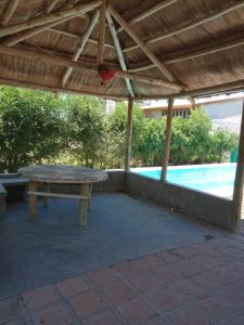 una mesa de picnic bajo una pérgola junto a una piscina en Flor Silvestre en Valle Hermoso