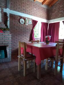comedor con mesa roja, sillas y chimenea en Flor Silvestre en Valle Hermoso