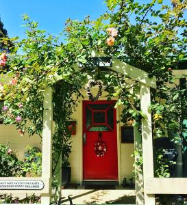 a red door on a white house with flowers at Kymmik Cottage in Geeveston