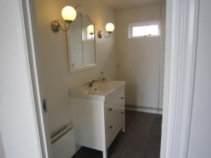 a white bathroom with a sink and a mirror at Apartment by the Sea in Höfn