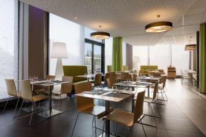 une salle à manger avec tables, chaises et fenêtres dans l'établissement Park Inn by Radisson Lille Grand Stade, à Villeneuve d'Ascq 14 autres photos