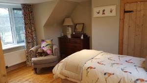 um quarto com uma cama, uma cadeira e uma janela em Gateshaw Cottage - Scottish Borders em Linton