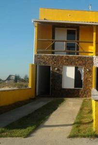 雅瓜魯納的住宿－Recanto das Pedras - Casa Pedra Ferrugem Com vista para o mar，黄色的建筑,一边有一扇门