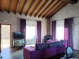 a living room with a purple couch and a tv at Esencia Mudayyan in Coca de Alba