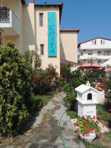 a sign for a hotel next to a garden at Studios Costa in Porto Koufo