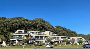 an apartment building in front of a mountain at Beachpoint Apartments in Ohope Beach