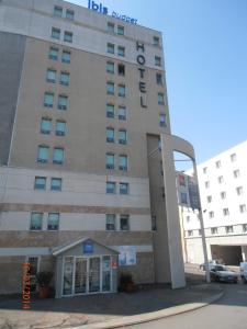 カリュイール・エ・キュイールにあるIbis Budget Lyon Caluire Cité Internationaleの標識が書かれた白い高い建物