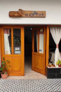 une entrée à un restaurant avec un panneau au-dessus de la porte dans l'établissement MAKTUB HOSTERIA, à El Bolsón