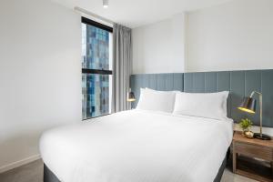 a white bed sitting in a bedroom next to a window at Brady Hotels Hardware Lane in Melbourne