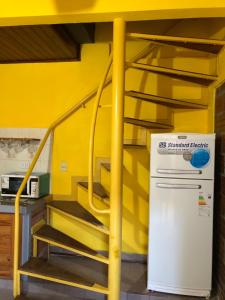 a yellow room with a stairs and a refrigerator at Chepoya Apart in Posadas +3 photos