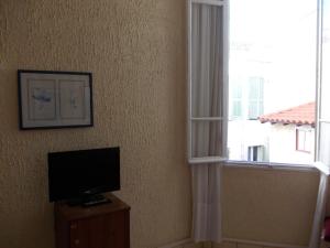 un salon avec une télévision et une fenêtre dans l'établissement L'Oursin, à Saint-Jean-Cap-Ferrat