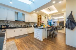 eine Küche mit weißen Schränken und eine Bar mit Hockern in der Unterkunft 25P Enchanting Bungalow Retreat - Mystical Garden,Petaling Jaya by Verano in Petaling Jaya