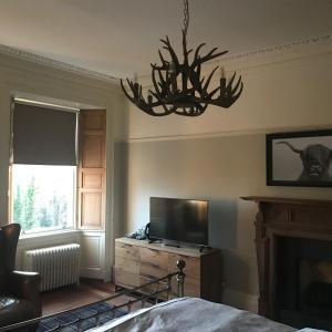 a bedroom with a television and a chandelier at Ashtree House Hotel, Glasgow Airport & Paisley in Paisley