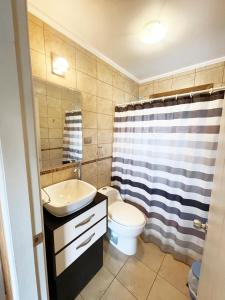 a bathroom with a sink and a toilet and a shower curtain at Waiwen in Pichilemu