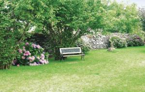 a park bench sitting in the grass next to a garden at Beautiful Home In Chateauneuf Du Faou With 5 Bedrooms And Wifi in Saint-Thois