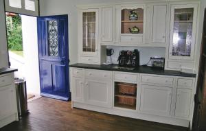 una cocina con armarios blancos y una puerta azul en Lovely Home In Chateauneuf Du Faou With Wifi, en Saint-Thois