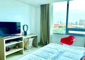 een slaapkamer met een bed en een televisie en een rode stoel bij Apartamento Moderno en Sector Norte de Barranquilla in Barranquilla