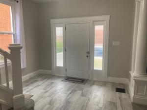 シンシナティにある6 BR Home Just Minutes From Downtown Cincinnatiの白いドアとウッドフロアの廊下