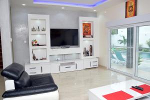 sala de estar con TV y sofá en Magnifique villa climatisée avec piscine à Warang - Villa Keur Damel et Linguère en Ouoran
