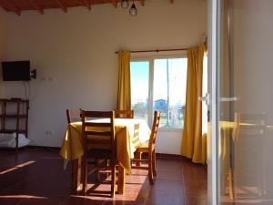 une salle à manger avec une table et des rideaux jaunes dans l'établissement Sandhikala -Camet Norte- Cabañas a 1 cuadra de la playa, estacionamiento en jardín privado,se aceptan mascotas, à Camet Norte