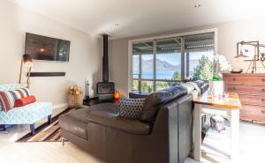 a living room with a leather couch and a fireplace at Private Cottage with Spa and Amazing Lake Views in Closeburn