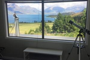 a camera in front of a window with a telescope at Private Cottage with Spa and Amazing Lake Views in Closeburn