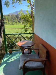 een tafel en een stoel op een veranda met een veld bij Pai Modern House in Pai