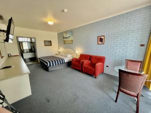 a hotel room with a bed and a red chair at Statesman Motor Inn in Ararat