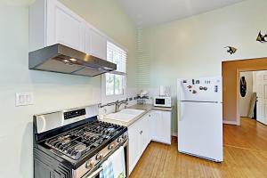 a white kitchen with a stove and a refrigerator at Under the Avenue in Galveston