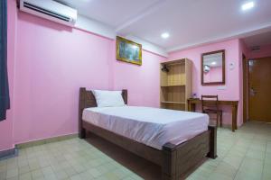 a bedroom with a pink wall with a bed and a desk at MK Inn Hotel in Kuala Lumpur