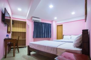 a bedroom with two beds and a table and a desk at MK Inn Hotel in Kuala Lumpur +7 photos