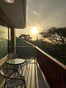 a balcony with two chairs and a table and the sunset at Fever Tree B&B in East London