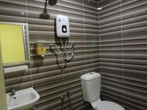 a bathroom with a toilet and a sink and a mirror at Comma Hotel in Bandar Saujana Putra