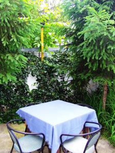 a table and chairs with a white table and trees at Hostel Domestika in Bitola