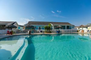 uma grande piscina com água azul em frente a uma casa em Jamaica Me Happy at Pirate's Bay Unit 303 em Port Aransas