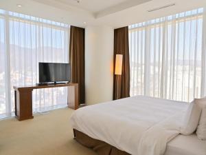 Schlafzimmer mit einem Bett und einem Flachbild-TV in der Unterkunft Ecograd Hotel in Suncheon