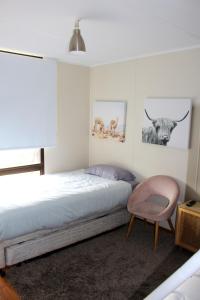 a bedroom with a bed and a pink chair at Investigator Beach Breeze Apartments U2 in Kingscote