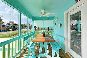 a blue porch with a wooden table and a ceiling fan at South Pearl Sailfish in Rockport