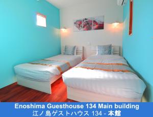 two beds in a room with blue walls at Enoshima Guest House 134 in Fujisawa