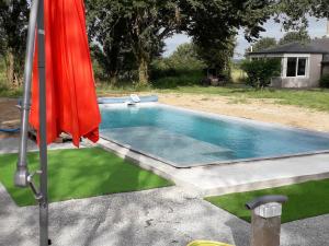 a swimming pool with a red umbrella next to it at Gîte Casson, 3 pièces, 4 personnes - FR-1-306-854 in Casson