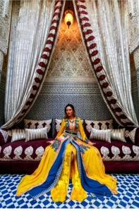 a woman sitting on a couch in a dress at Riad Fes Nass Zmane in Fez