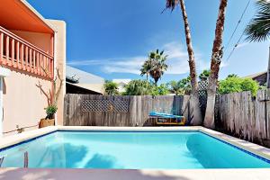 a swimming pool in a backyard with a fence and palm trees at Lantana Unit B in South Padre Island