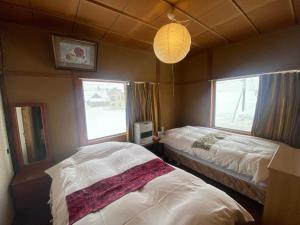 a bedroom with two beds and a lamp and two windows at HAKUBA Raicho Star in Hakuba